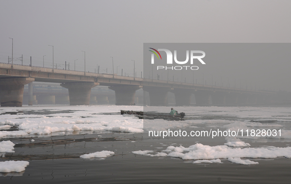 A man rows a boat in the river Yamuna, which is covered in toxic foam, in New Delhi, India, on November 7, 2024. 