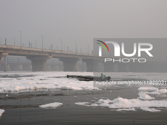 A man rows a boat in the river Yamuna, which is covered in toxic foam, in New Delhi, India, on November 7, 2024. (