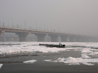 A man rows a boat in the river Yamuna, which is covered in toxic foam, in New Delhi, India, on November 7, 2024. (