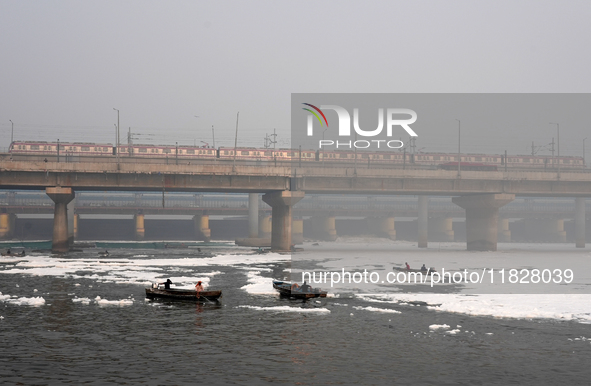 Workers for the Delhi water board move in a boat spraying defoaming chemicals to remove the toxic foam flowing in the Yamuna River in New De...