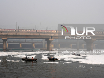 Workers for the Delhi water board move in a boat spraying defoaming chemicals to remove the toxic foam flowing in the Yamuna River in New De...