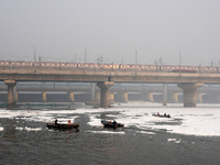 Workers for the Delhi water board move in a boat spraying defoaming chemicals to remove the toxic foam flowing in the Yamuna River in New De...