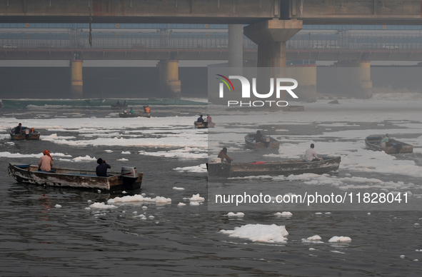 Workers for the Delhi water board move in boats to remove the toxic foam flowing in the Yamuna River in New Delhi, India, on November 7, 202...