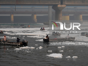 Workers for the Delhi water board move in boats to remove the toxic foam flowing in the Yamuna River in New Delhi, India, on November 7, 202...