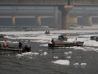 Workers for the Delhi water board move in boats to remove the toxic foam flowing in the Yamuna River in New Delhi, India, on November 7, 202...