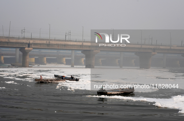 Workers for the Delhi water board move in boats to remove the toxic foam flowing in the Yamuna River in New Delhi, India, on November 7, 202...