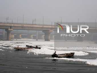 Workers for the Delhi water board move in boats to remove the toxic foam flowing in the Yamuna River in New Delhi, India, on November 7, 202...