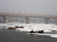 Workers for the Delhi water board move in boats to remove the toxic foam flowing in the Yamuna River in New Delhi, India, on November 7, 202...