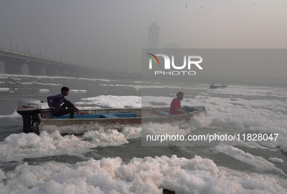 Workers for the Delhi water board move in a boat spraying defoaming chemicals to remove the toxic foam flowing in the Yamuna River in New De...