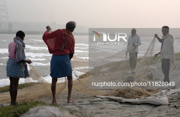 Fishermen prepare their fishing net on the bank of the Yamuna River, which is filled with toxic foam, in New Delhi, India, on November 7, 20...