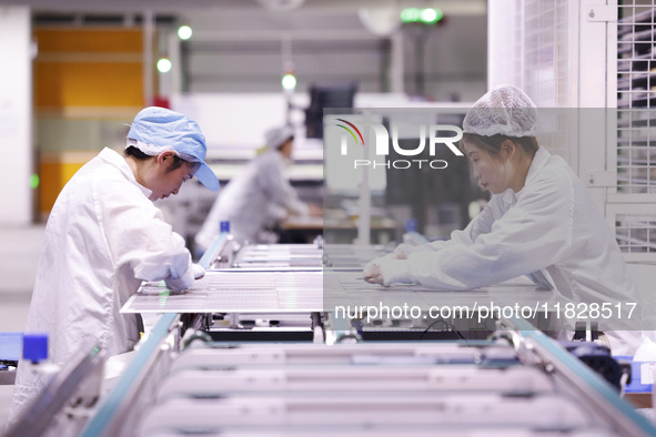 Workers produce export photovoltaic modules in a new energy 5G intelligent workshop in Suqian, China, on December 2, 2024. 