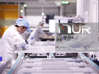 Workers produce export photovoltaic modules in a new energy 5G intelligent workshop in Suqian, China, on December 2, 2024. (