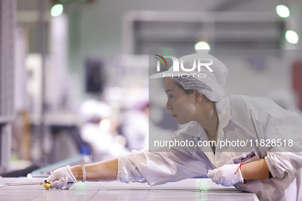 Workers produce export photovoltaic modules in a new energy 5G intelligent workshop in Suqian, China, on December 2, 2024. 