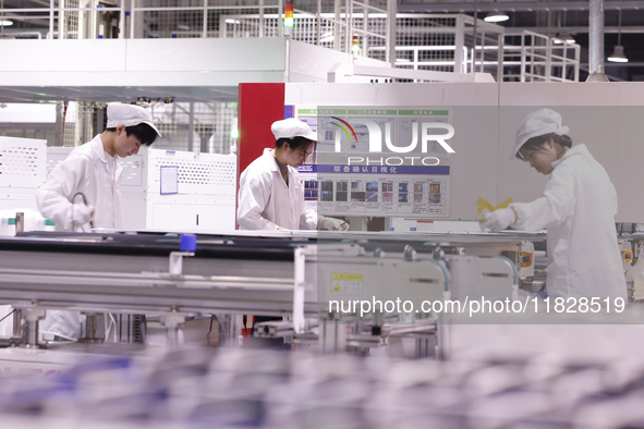 Workers produce export photovoltaic modules in a new energy 5G intelligent workshop in Suqian, China, on December 2, 2024. 