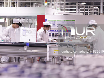 Workers produce export photovoltaic modules in a new energy 5G intelligent workshop in Suqian, China, on December 2, 2024. (