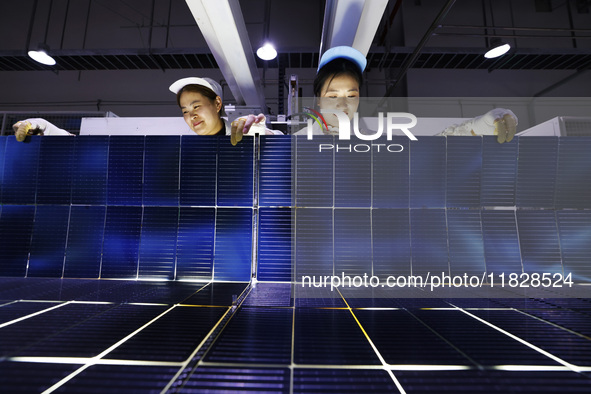 Workers produce export photovoltaic modules in a new energy 5G intelligent workshop in Suqian, China, on December 2, 2024. 