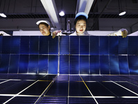 Workers produce export photovoltaic modules in a new energy 5G intelligent workshop in Suqian, China, on December 2, 2024. (