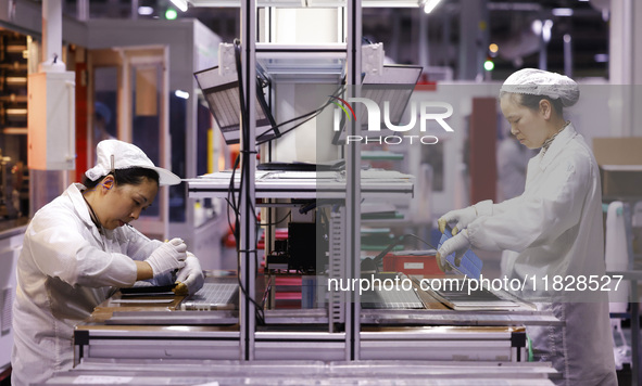 Workers produce export photovoltaic modules in a new energy 5G intelligent workshop in Suqian, China, on December 2, 2024. 