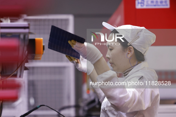 Workers produce export photovoltaic modules in a new energy 5G intelligent workshop in Suqian, China, on December 2, 2024. 