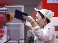 Workers produce export photovoltaic modules in a new energy 5G intelligent workshop in Suqian, China, on December 2, 2024. (