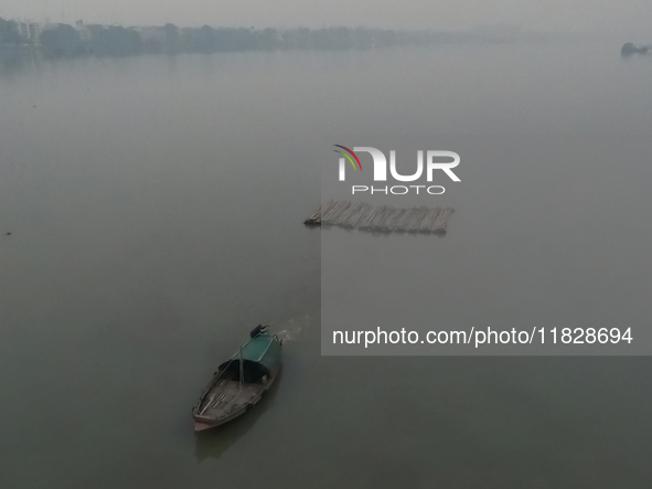 A boat transports bamboo across the Ganga River on a dense, foggy morning amid rising air pollution levels in Kolkata, India, on December 02...