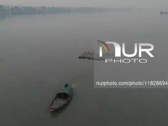 A boat transports bamboo across the Ganga River on a dense, foggy morning amid rising air pollution levels in Kolkata, India, on December 02...