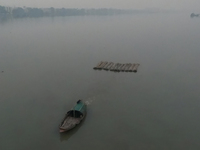 A boat transports bamboo across the Ganga River on a dense, foggy morning amid rising air pollution levels in Kolkata, India, on December 02...