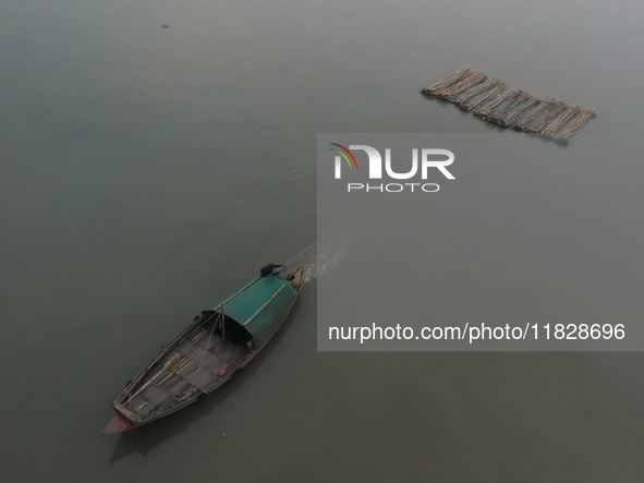 A boat transports bamboo across the Ganga River on a dense, foggy morning amid rising air pollution levels in Kolkata, India, on December 02...