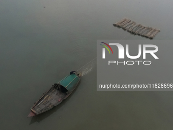 A boat transports bamboo across the Ganga River on a dense, foggy morning amid rising air pollution levels in Kolkata, India, on December 02...