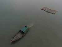 A boat transports bamboo across the Ganga River on a dense, foggy morning amid rising air pollution levels in Kolkata, India, on December 02...