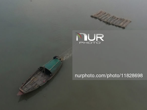 A boat transports bamboo across the Ganga River on a dense, foggy morning amid rising air pollution levels in Kolkata, India, on December 02...