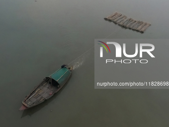 A boat transports bamboo across the Ganga River on a dense, foggy morning amid rising air pollution levels in Kolkata, India, on December 02...