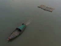 A boat transports bamboo across the Ganga River on a dense, foggy morning amid rising air pollution levels in Kolkata, India, on December 02...