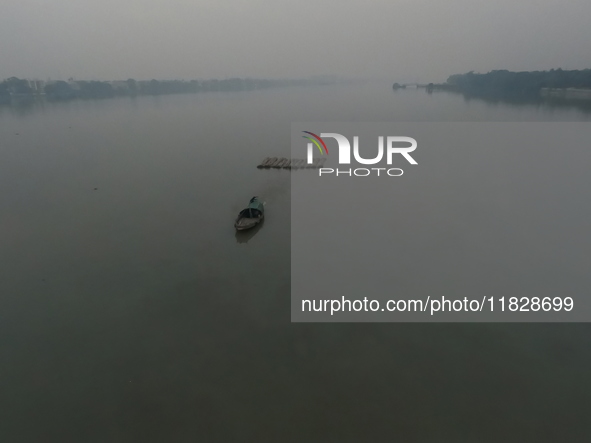 A boat transports bamboo across the Ganga River on a dense, foggy morning amid rising air pollution levels in Kolkata, India, on December 02...