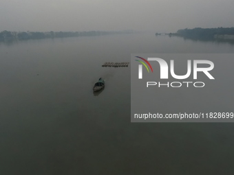 A boat transports bamboo across the Ganga River on a dense, foggy morning amid rising air pollution levels in Kolkata, India, on December 02...