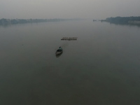 A boat transports bamboo across the Ganga River on a dense, foggy morning amid rising air pollution levels in Kolkata, India, on December 02...