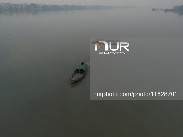 A boat transports bamboo across the Ganga River on a dense, foggy morning amid rising air pollution levels in Kolkata, India, on December 02...