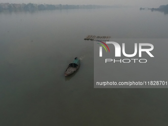 A boat transports bamboo across the Ganga River on a dense, foggy morning amid rising air pollution levels in Kolkata, India, on December 02...