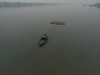 A boat transports bamboo across the Ganga River on a dense, foggy morning amid rising air pollution levels in Kolkata, India, on December 02...