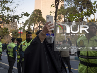 Iranian policemen stand guard outside the Turkish embassy while a veiled woman records video with her cellphone during a protest against Tur...