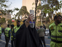 Iranian policemen stand guard outside the Turkish embassy while a veiled woman records video with her cellphone during a protest against Tur...