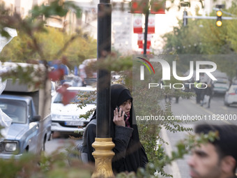 A veiled Iranian woman speaks on her cellphone during a protest against Turkish President Recep Tayyip Erdogan and his diplomacy regarding r...