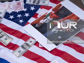 Copies of the U.S. Dollar, Turkish Lira banknotes, and an anti-Turkish President poster are placed by Iranian protesters on the U.S. flag du...