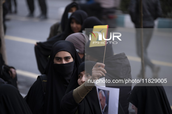 A veiled Iranian protester waves a flag of Lebanon's Hezbollah while taking part in a protest against Turkish President Recep Tayyip Erdogan...