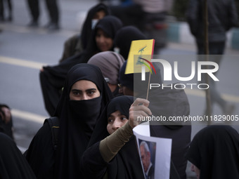 A veiled Iranian protester waves a flag of Lebanon's Hezbollah while taking part in a protest against Turkish President Recep Tayyip Erdogan...