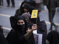 A veiled Iranian protester waves a flag of Lebanon's Hezbollah while taking part in a protest against Turkish President Recep Tayyip Erdogan...