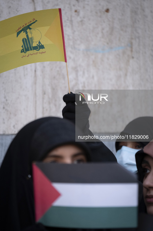 A veiled Iranian protester waves a flag of Lebanon's Hezbollah while taking part in a protest against Turkish President Recep Tayyip Erdogan...