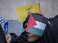 A veiled Iranian protester waves a Palestinian flag while participating in a protest against Turkish President Recep Tayyip Erdogan and his...