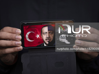 An Iranian protester holds a cellphone displaying an anti-Turkish President poster while participating in a protest against Turkish Presiden...