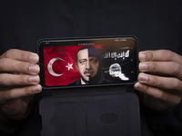 An Iranian protester holds a cellphone displaying an anti-Turkish President poster while participating in a protest against Turkish Presiden...